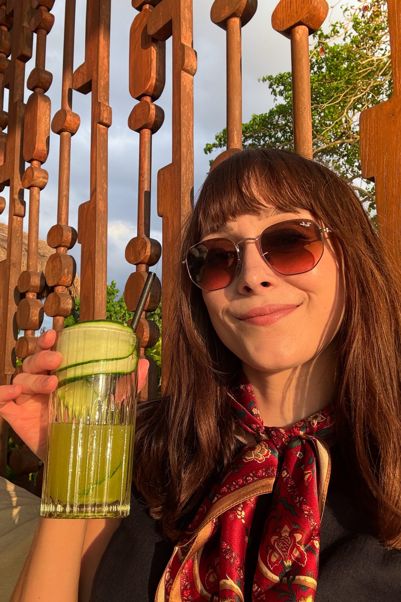 Travel Blogger Jordan Gassner smiling and holding a green juice with cucumbers from the Cap Karoso Beach Club in Sumba, Indonesia