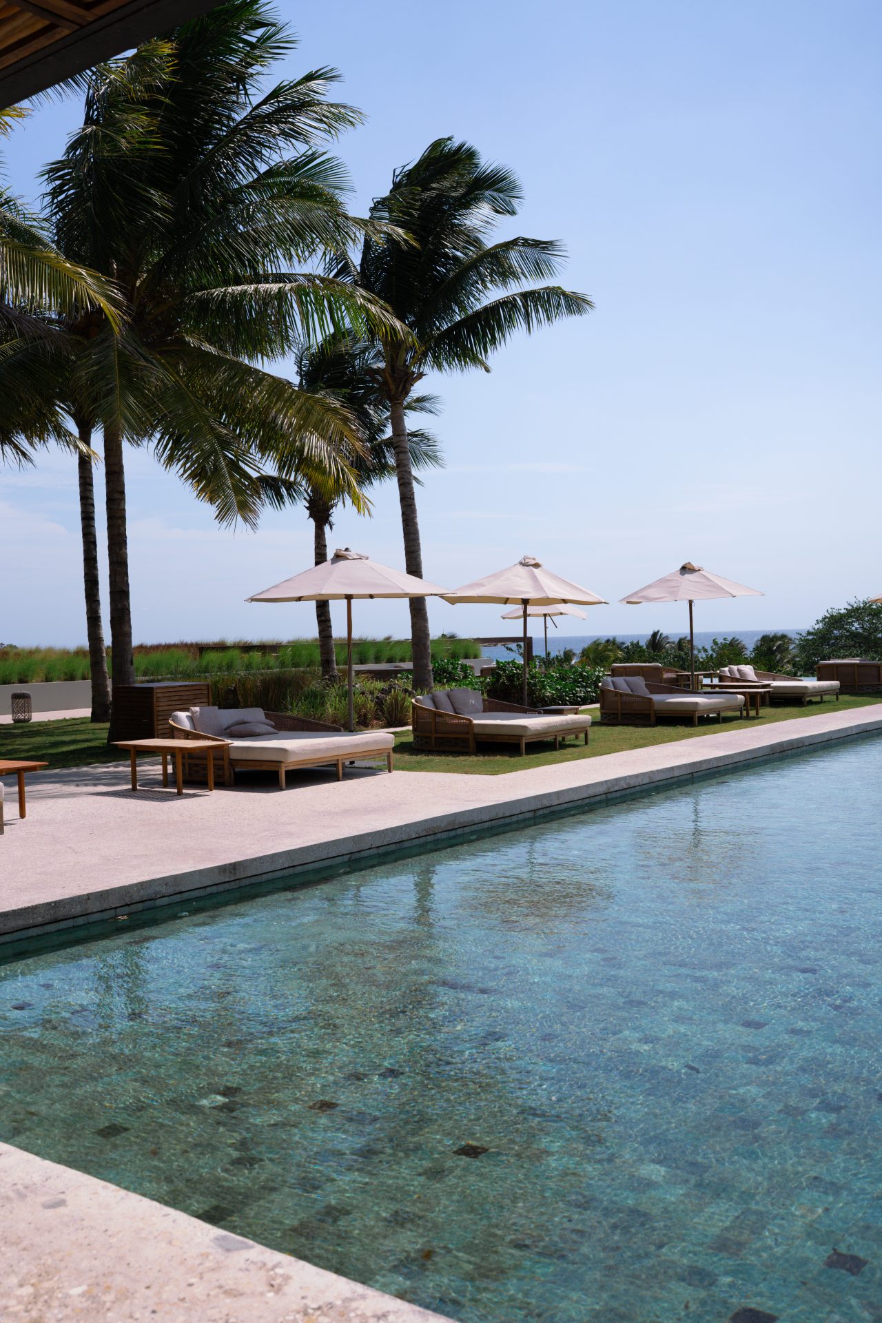 A group of loungers and day beds under umbrellas in front of an empty infinity pool at Cap Karoso resort in Sumba, Indonesia