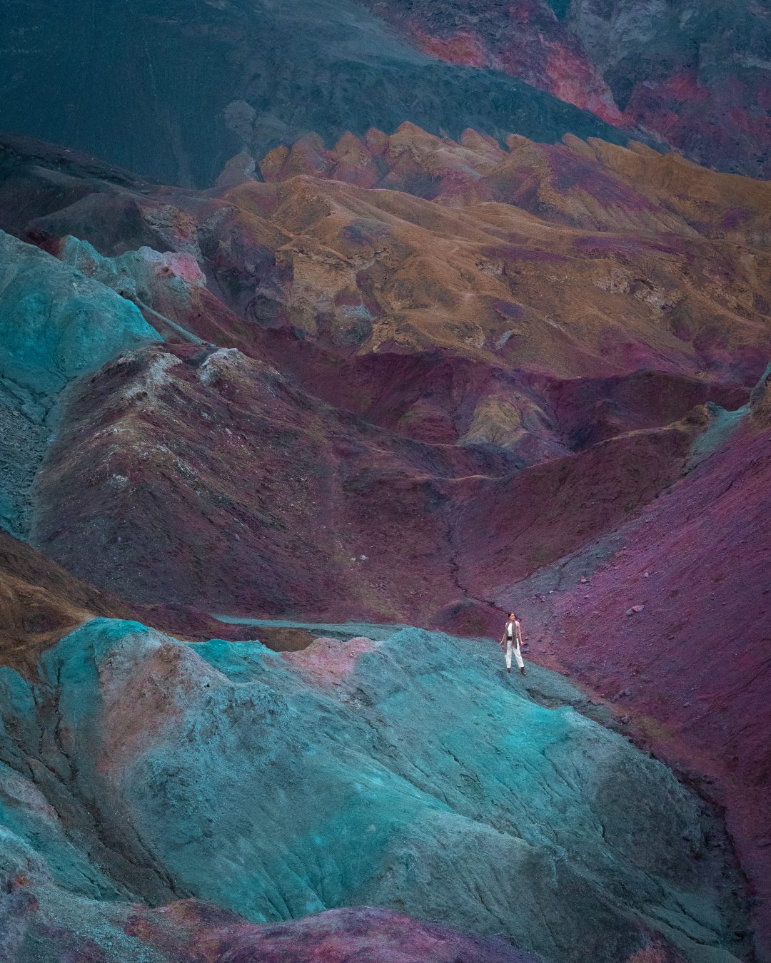 Travel Blogger Jordan Gassner standing along a pathway in between the colorful hills of Artist's Palette in Death Valley, California