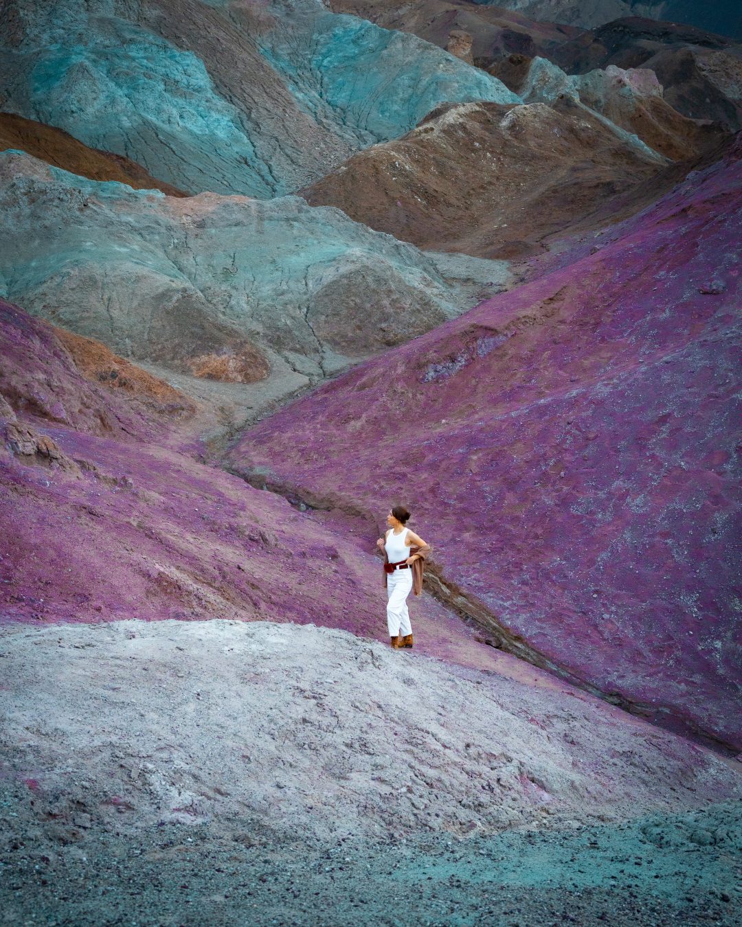 Travel Blogger Jordan Gassner walking up a blue colorful hill at Artist's Palette in Death Valley, California