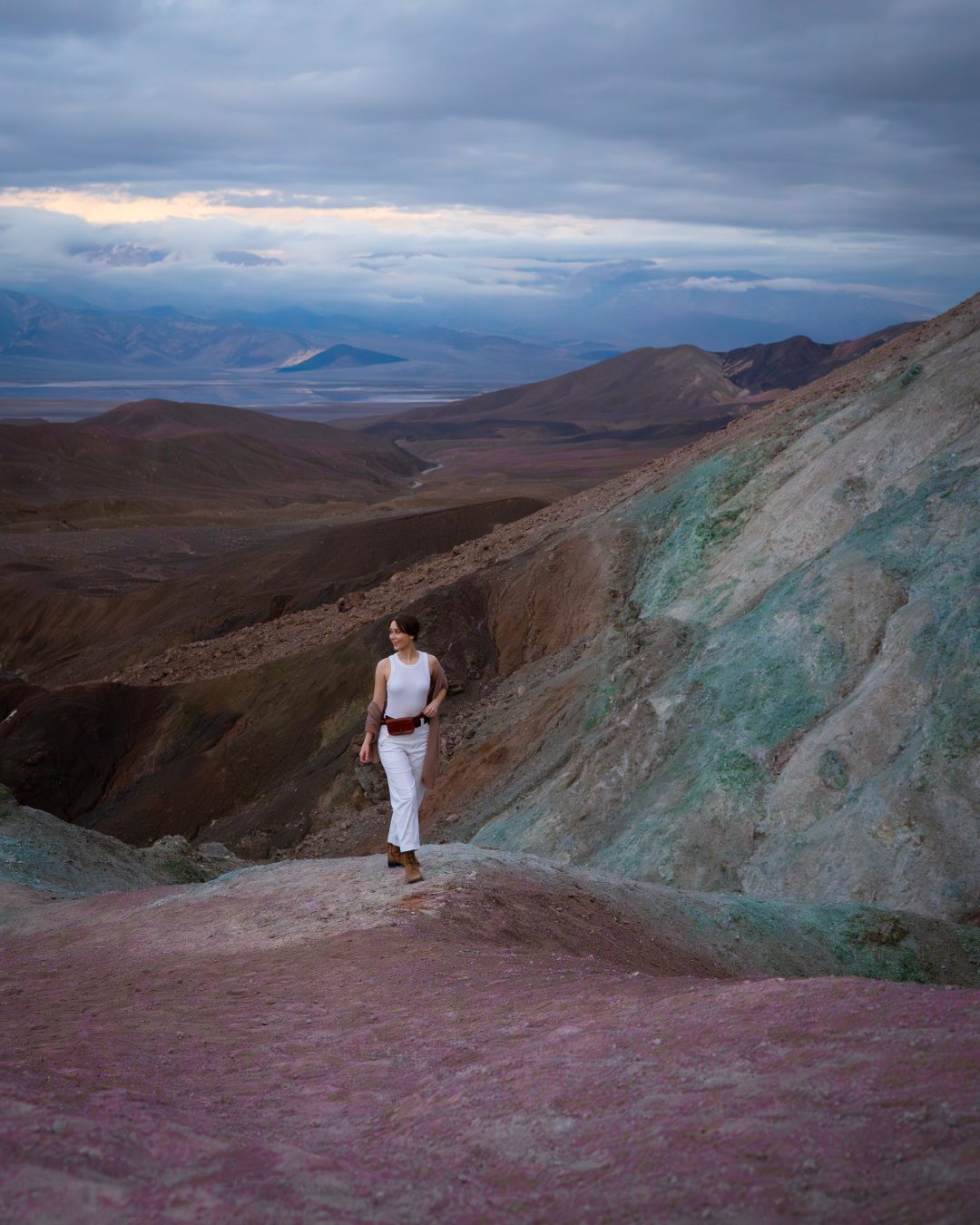 Travel Blogger Jordan Gassner walking along a purple ledge at the edge of Artist's Palette in Death Valley, California