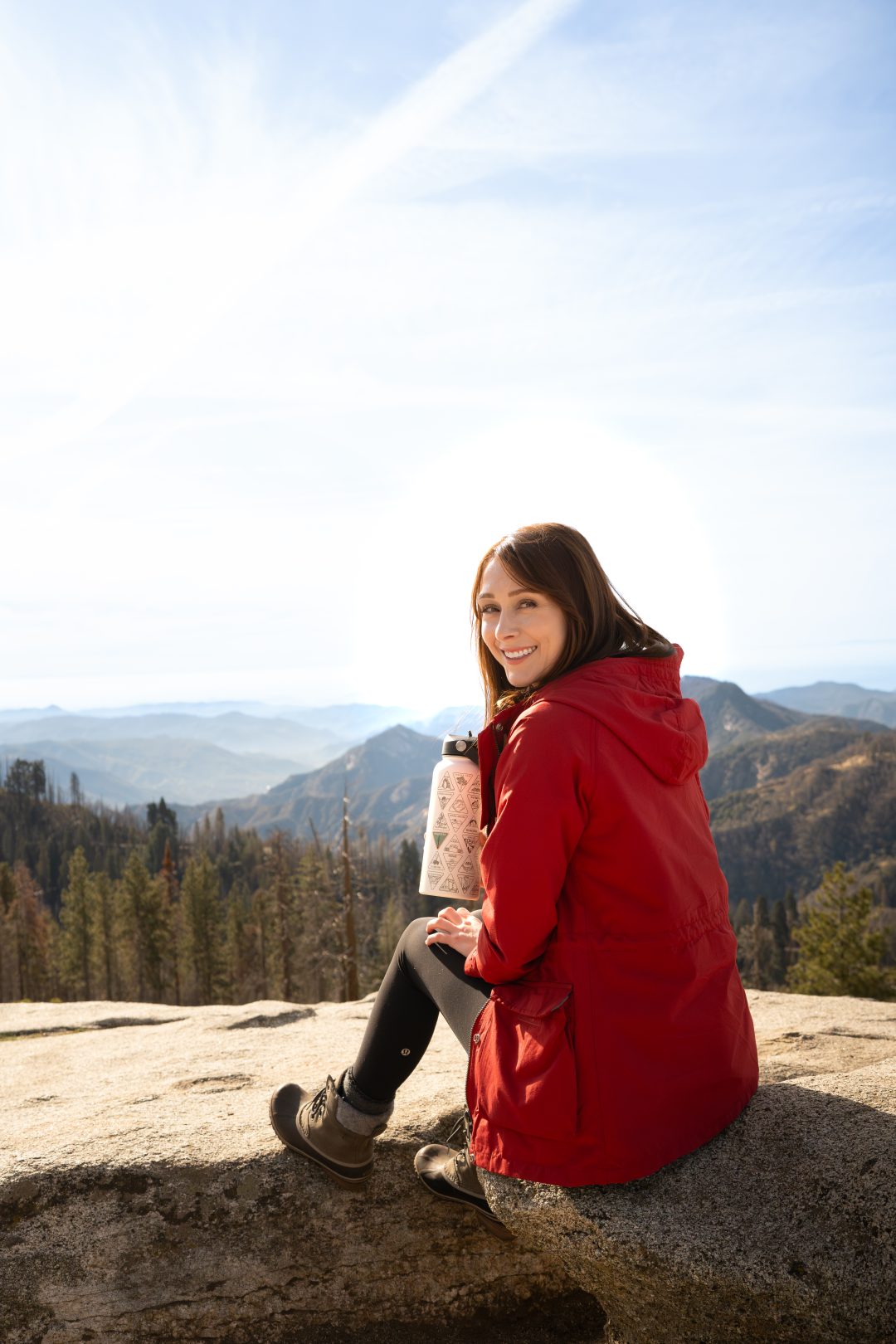 Travel Blogger Jordan Gassner sitting on top of Beetle Rock with a National Parks water bottle inside Sequoia National Park in California