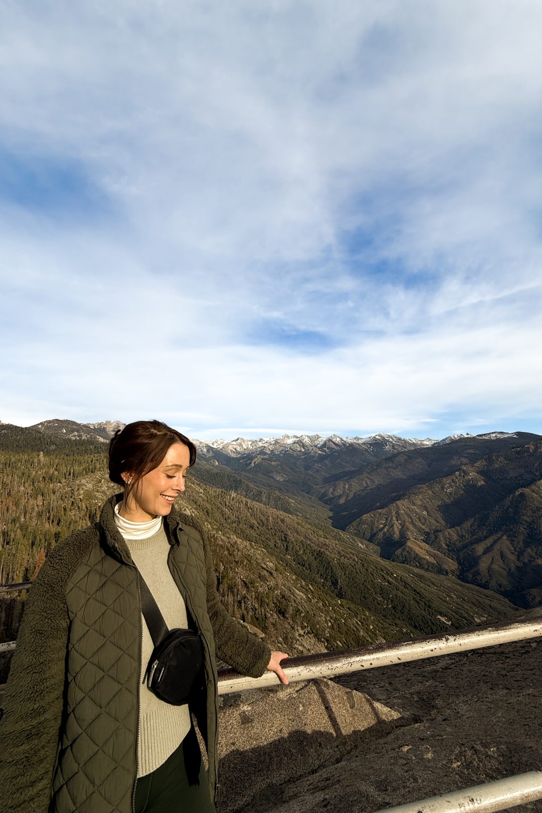 Travel Blogger Jordan Gassner smiling while holding the railing along the trail at the top of Moro Rock during her first time in Sequoia National Park