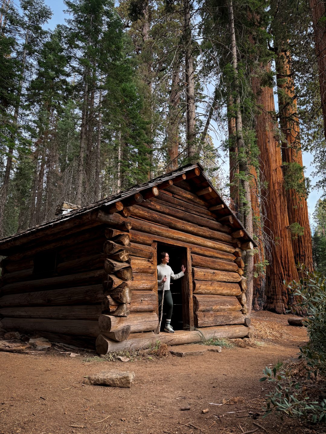 Guide to Sequoia's Best Trails: Travel Blogger Jordan Gassner looking out from the doorway of Squatter's Cabin in Sequoia National Park