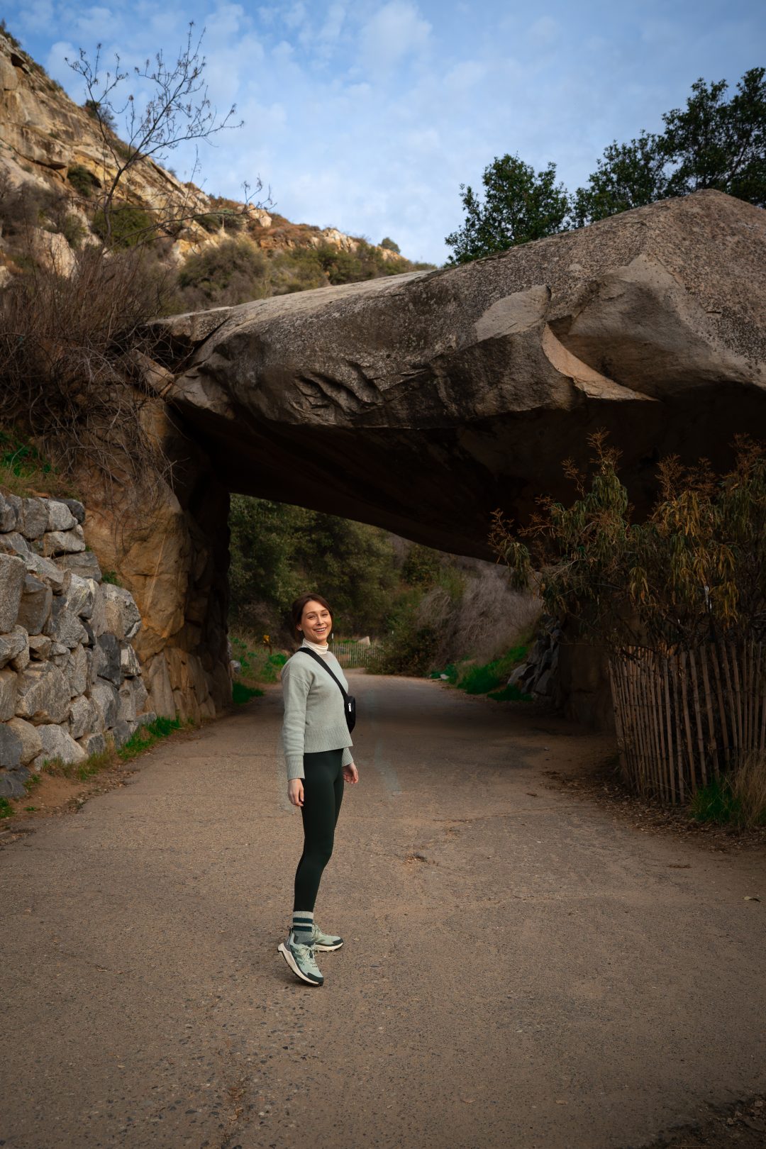 Travel Blogger Jordan Gassner looking over her shoulder and smiling while walking toward Tunnel Rock in Sequoia National Park