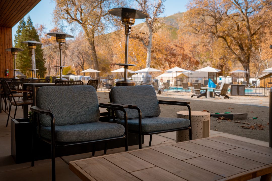 A table and set of ourdoor chairs and space heaters near an outdoor pool at AutoCamp Sequoia in Three Rivers, California