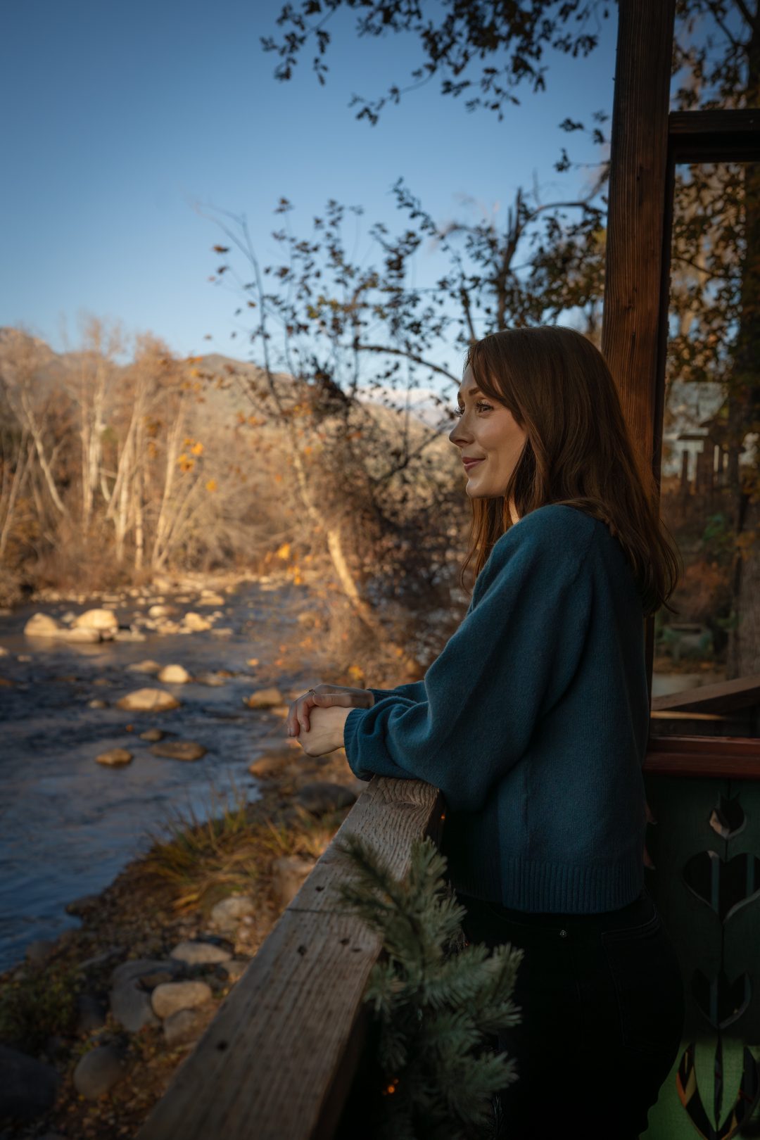 Travel Blogger Jordan Gassner looking out at the river while leaning againsta balcony in the back of Reimer's Candies and Gifts in Three Rivers, California