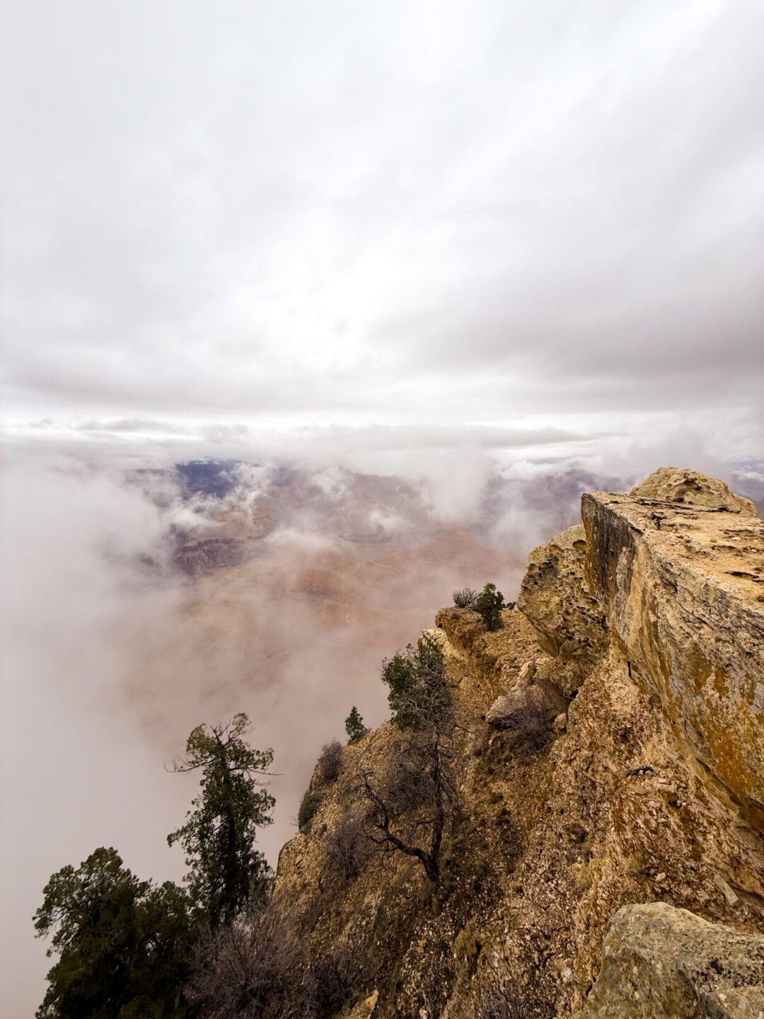 A cliff near Mather Point with the view of the Grand Canyon beyond obscured by low clouds