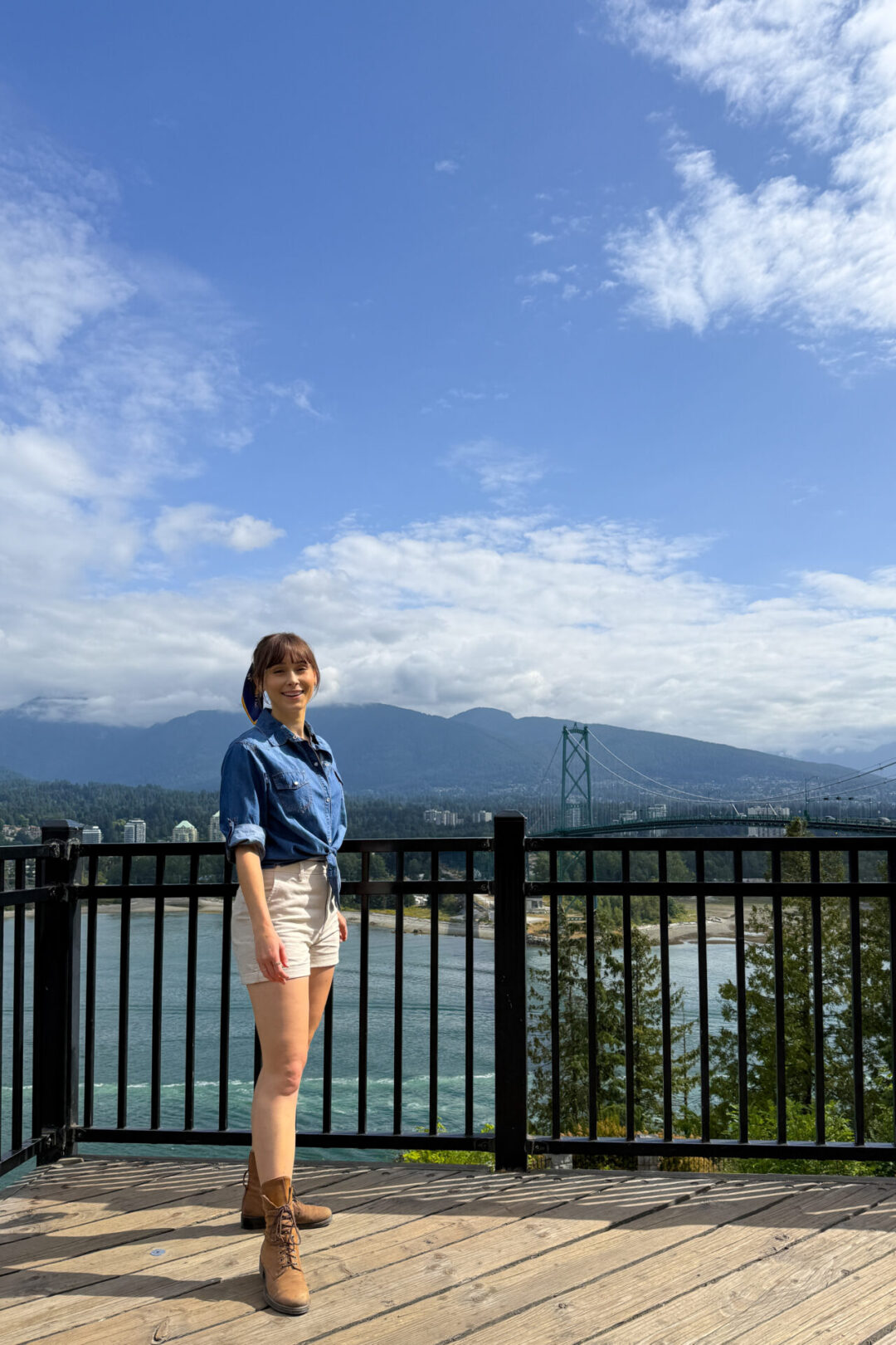 Jordan Gassner smiling from a platform in the heart of Stanley Park that looks out toward Lions Gate Bridge