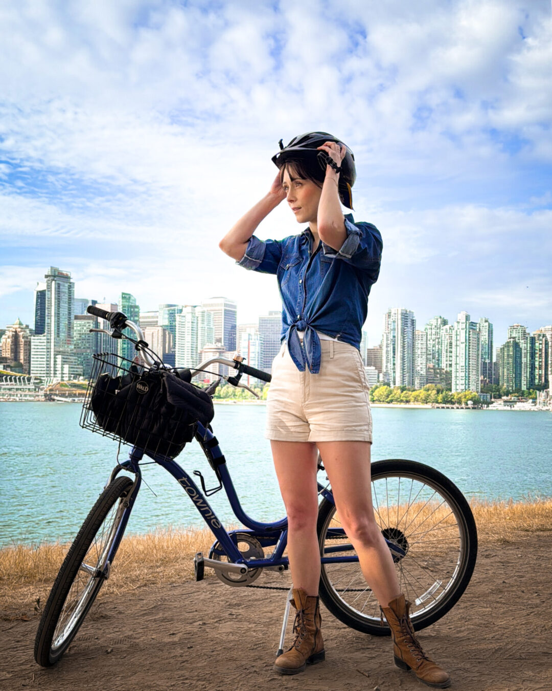 Travel Blogger Jordan Gassner putting on her helmet in front of her bike rental at Hallelujah Point in Stanley Park, Vancouver, Canada