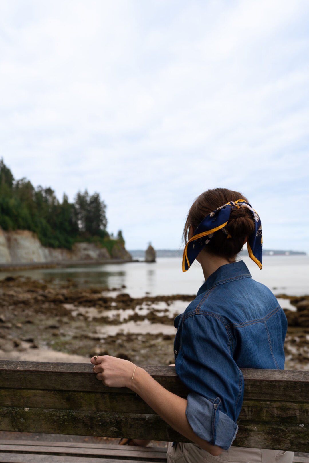 Travel Blogger Jordan Gassner sitting on a bench and looking toward Siwash Rock in Vancouver, Canada