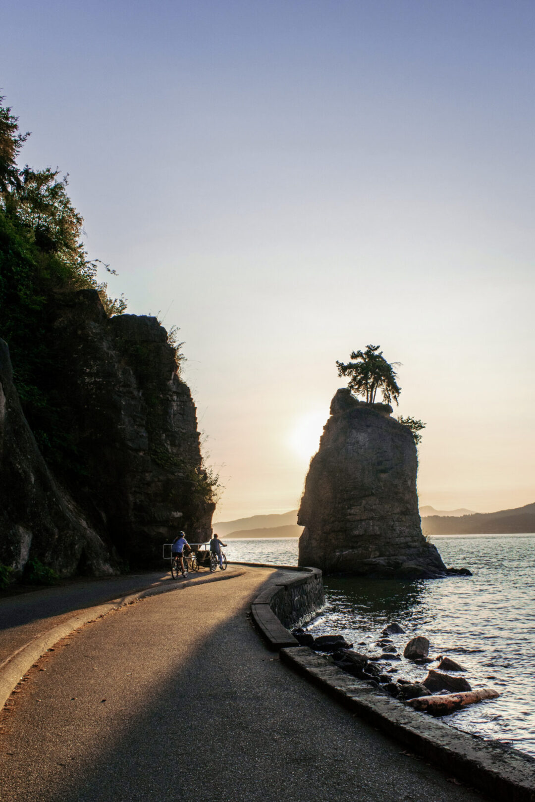 The sun setting behind Siwash Rock as seen from the Seawall in Stanley Park, Vancouver, Canada