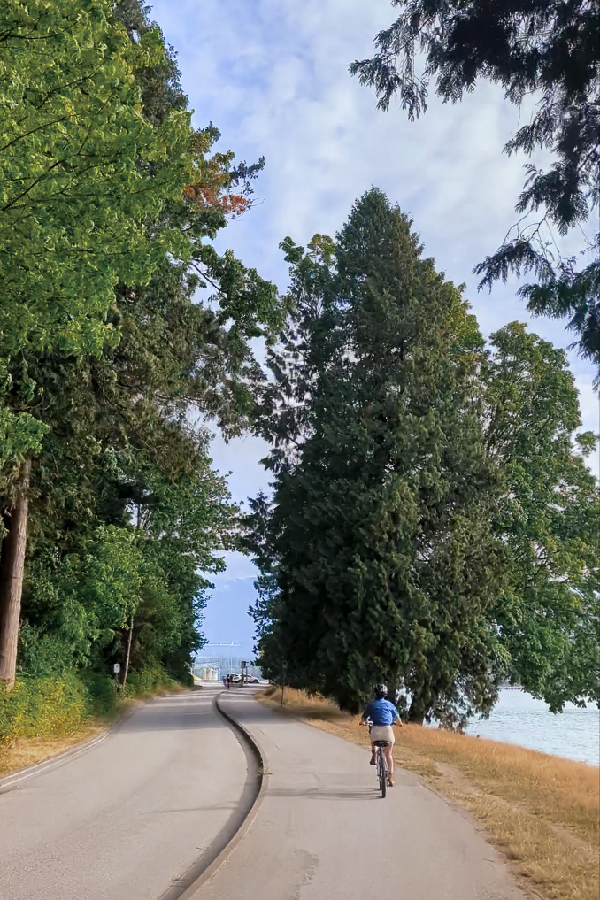 Travel Blogger Jordan Gassner cruising down the Seawall bike path next to the water around Stanley Park in Vancouver, Canada