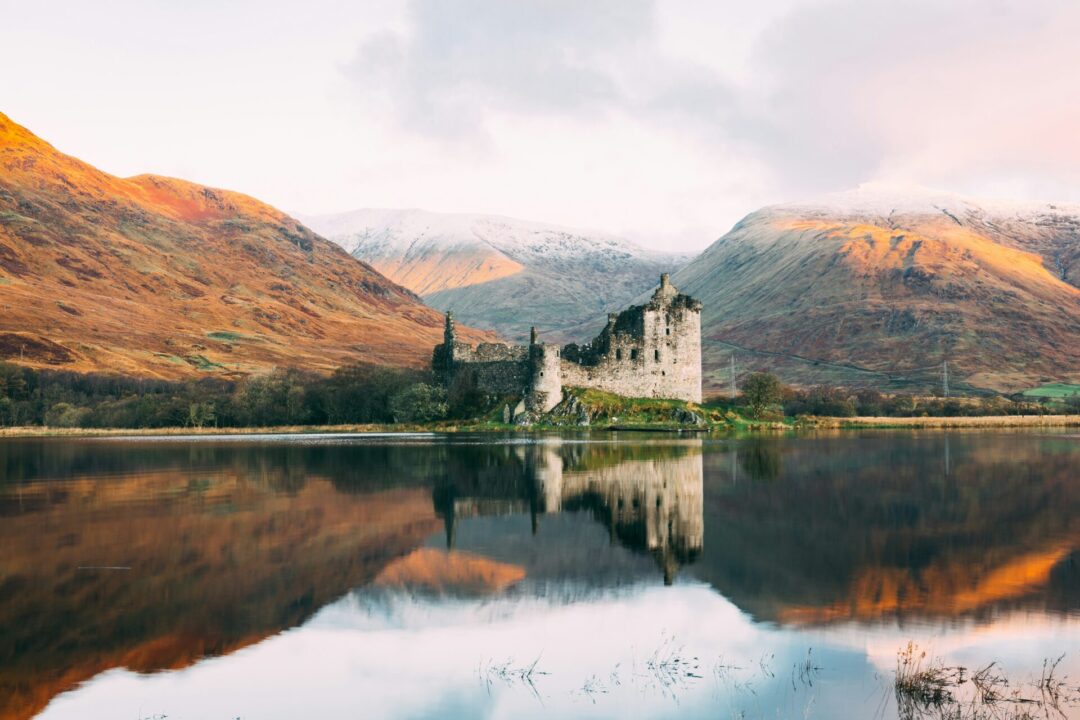 10 Best Solo Travel Countries For First-Timers: Eilean Donan Castle reflected off a  lake in Scotland