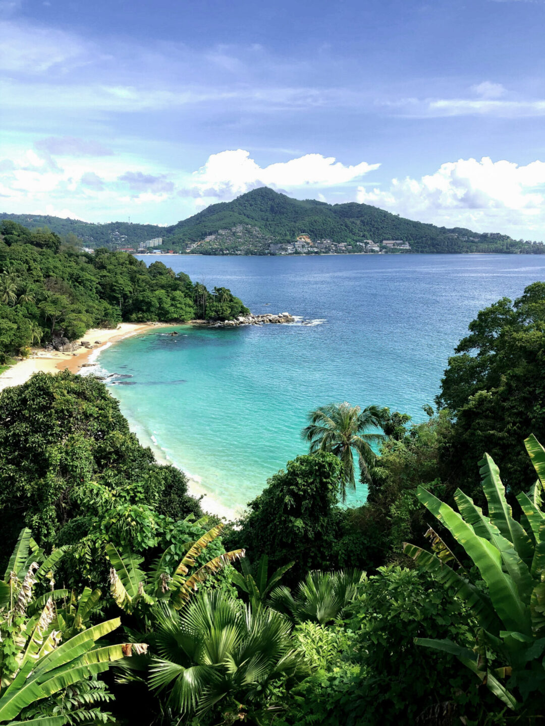 A beach in Thailand surrounded by lush vegtation and hills