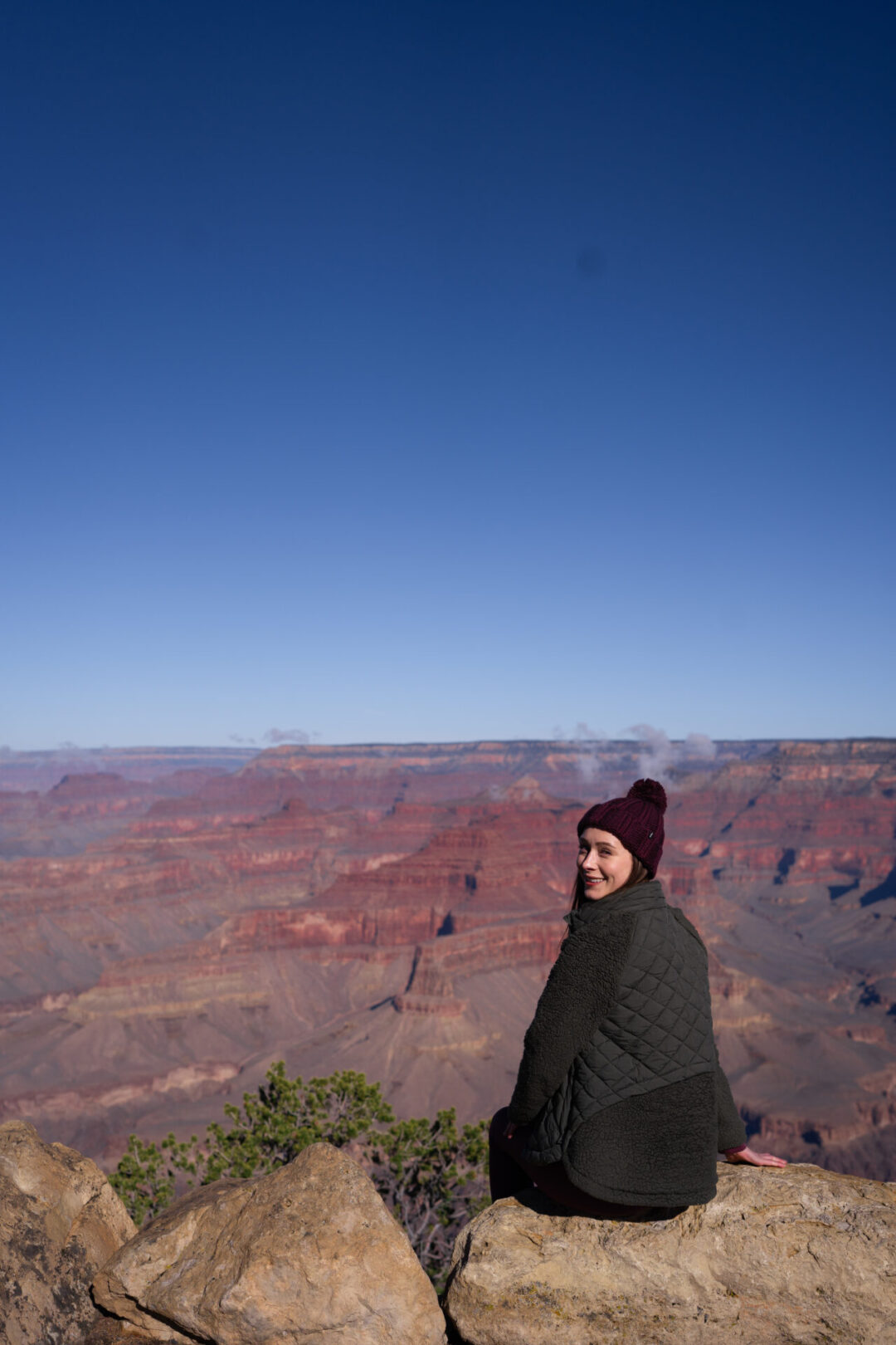 Travel Blogger Jordan Gassner smiling and looking over her shoulder at Powell Viewpoint in the Grand Canyon