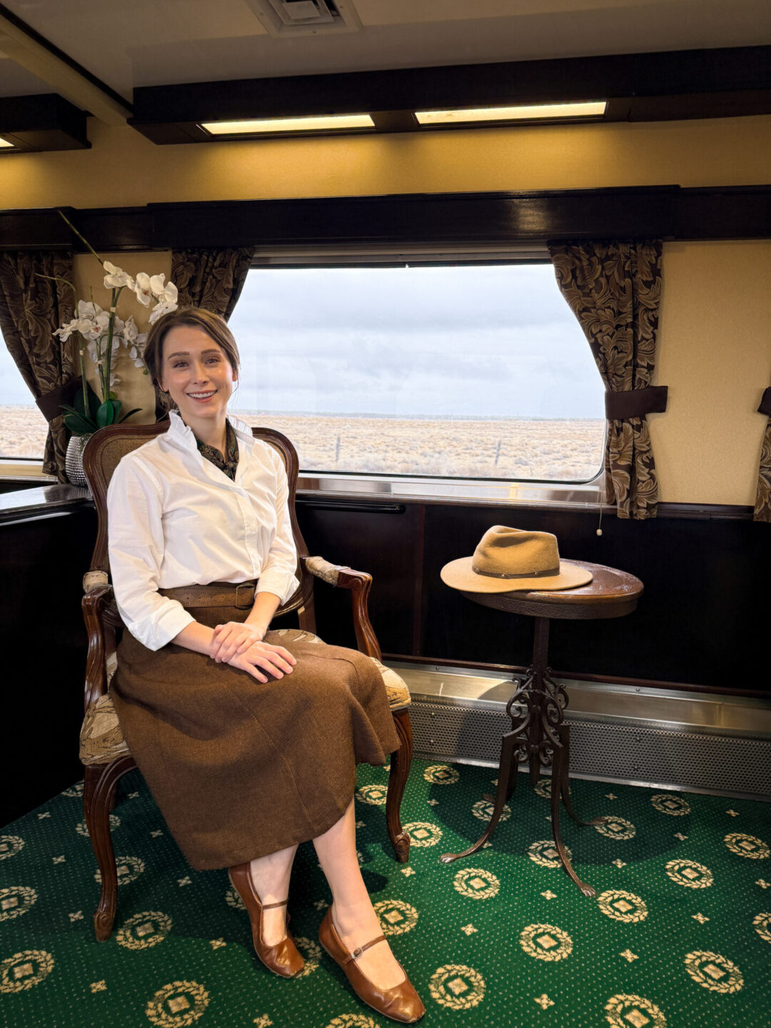 Travel Blogger Jordan Gassner smiling from an armchair inside a luxury parlor car aboard the Grand Canyon Railway