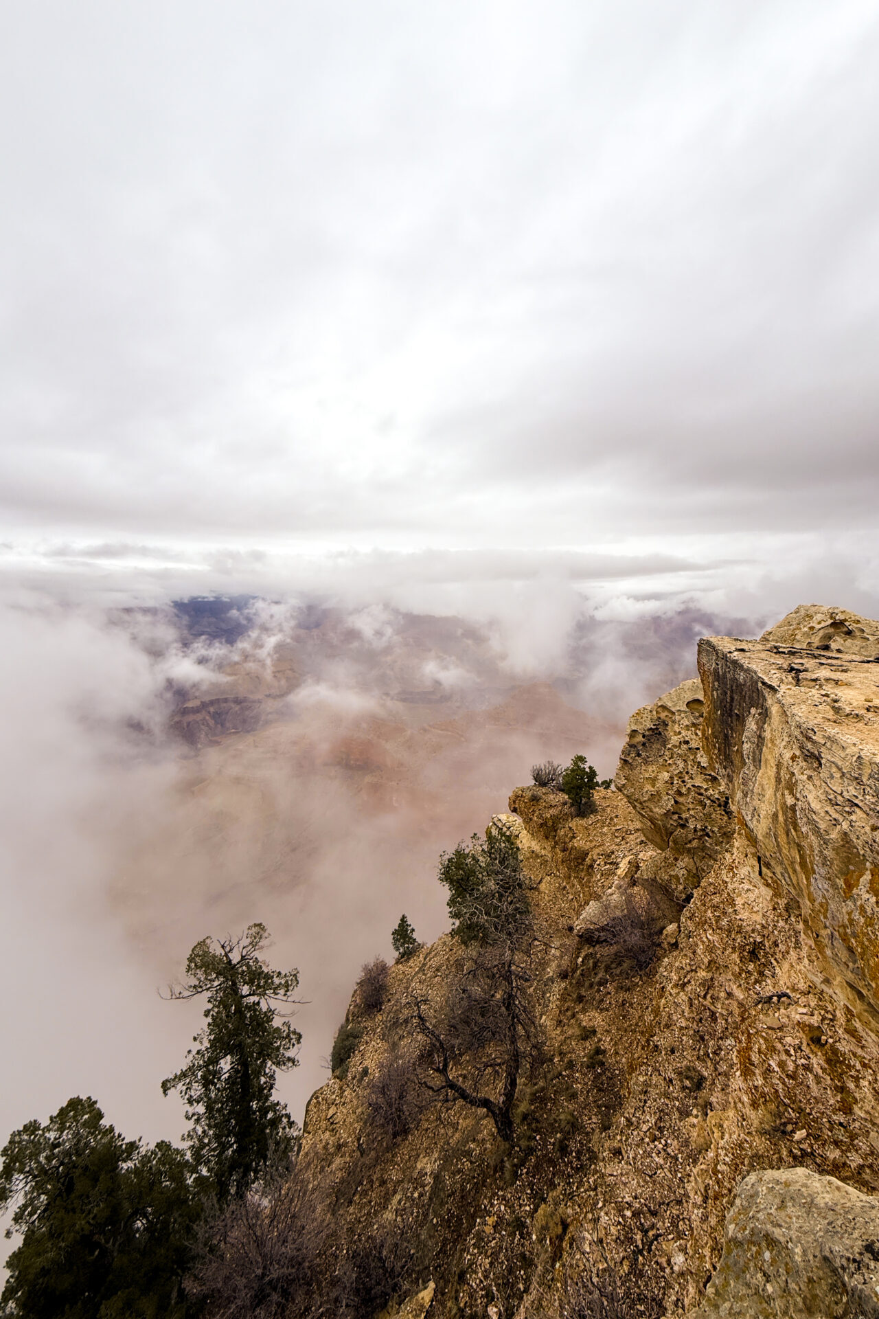 A cliff near Mather Point with the view of the Grand Canyon beyond obscured by low clouds