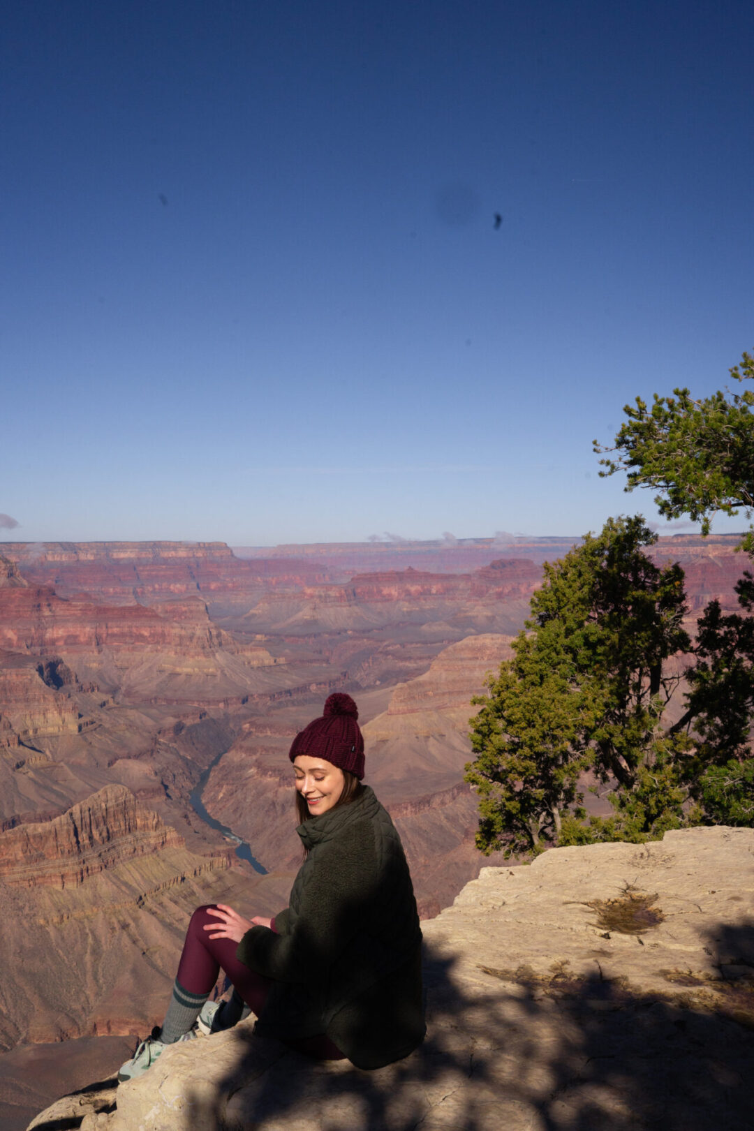 Travel Blogger Jordan Gassner smiling and turning around while sitting at Mohave Viewpoint at the Grand Canyon