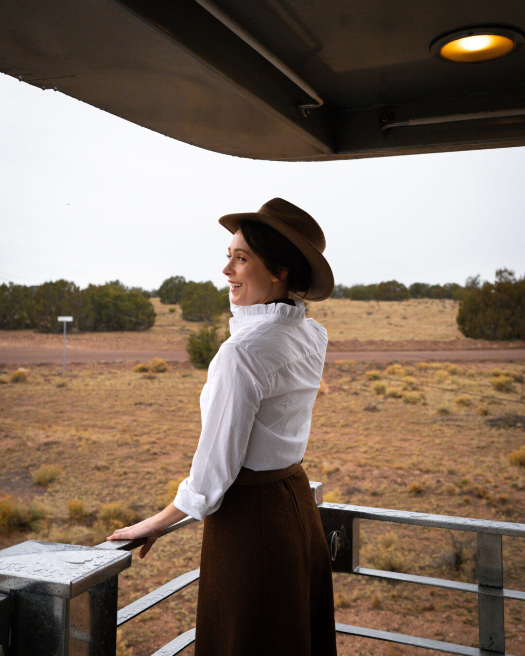 Travel Blogger Jordan Gassner wearing a cowboy hat while standing on the back observation deck while traveling along the Grand Canyon Railway