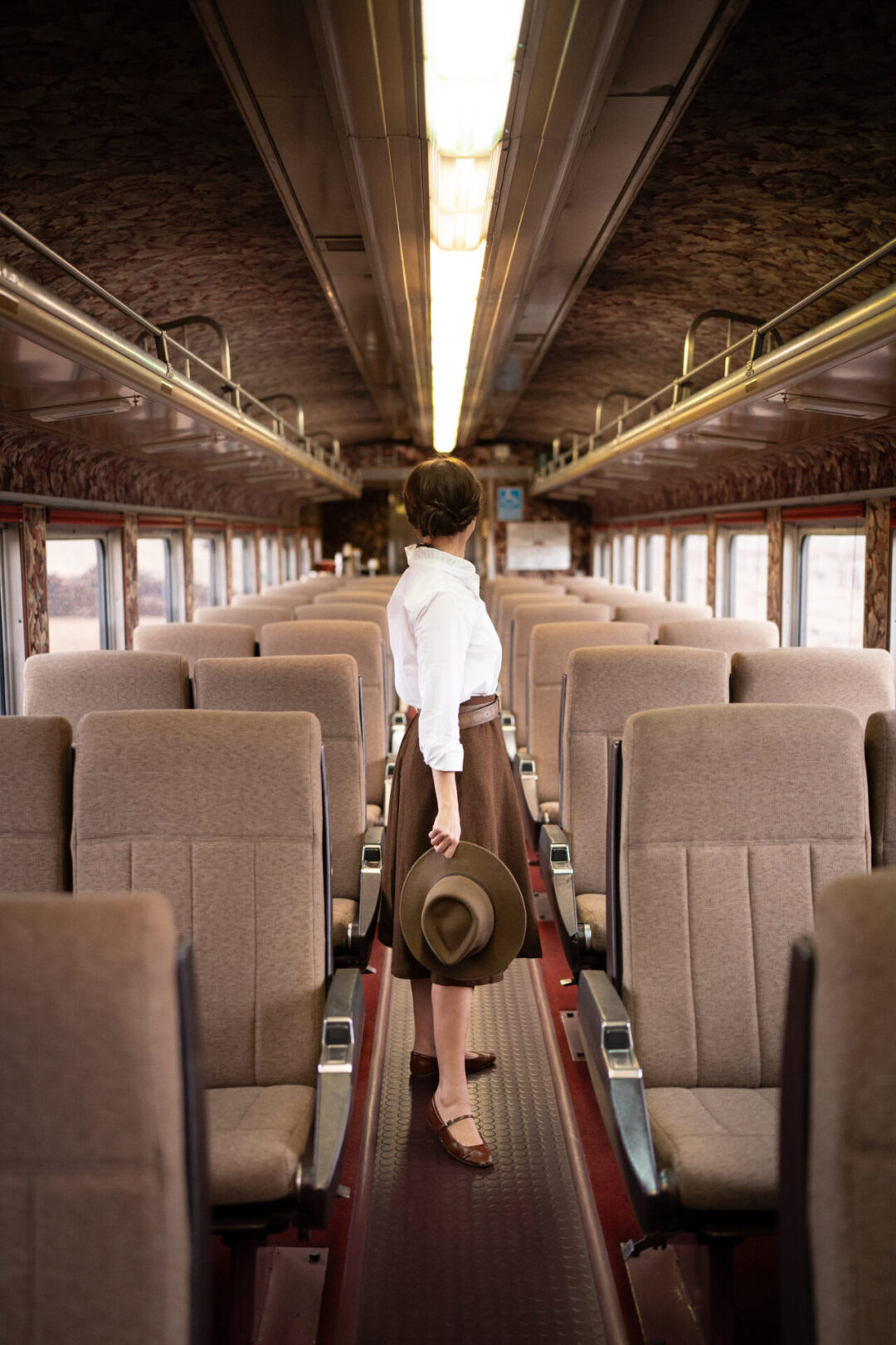 Travel Blogger Jordan Gassner looking over her shoulder while walking down an aisle of a First Class car aboard the Grand Canyon Railway