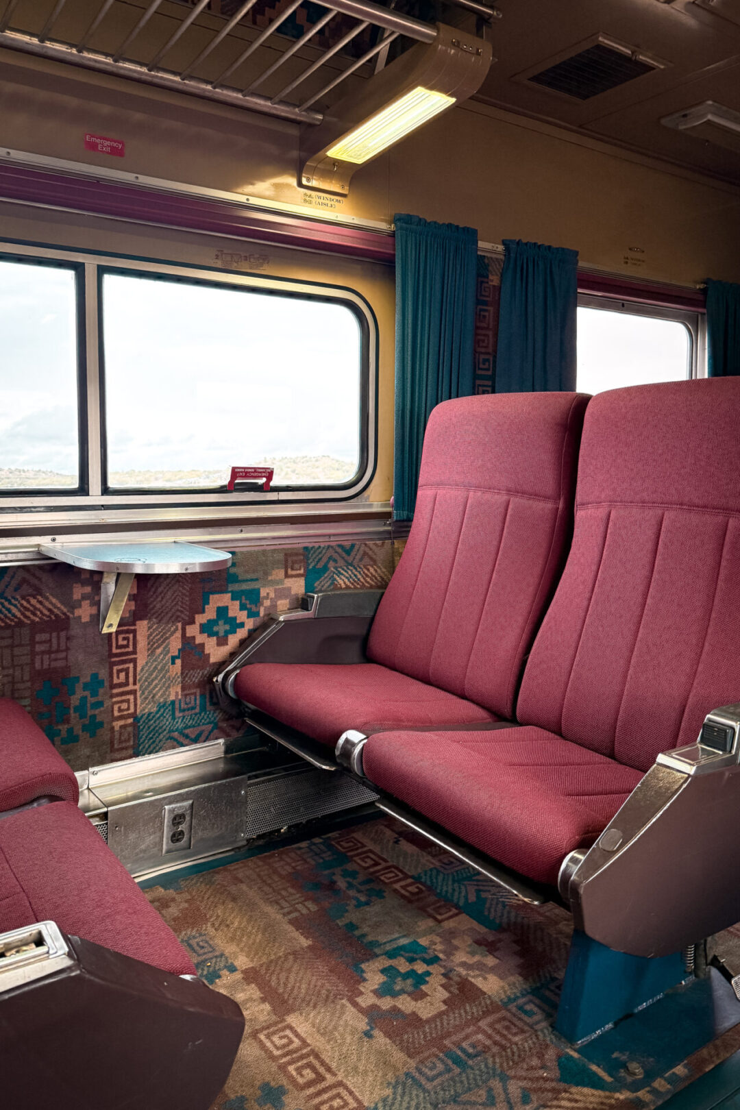 Pink seats and a tray table inside a First Class car inside the Grand Canyon Railway