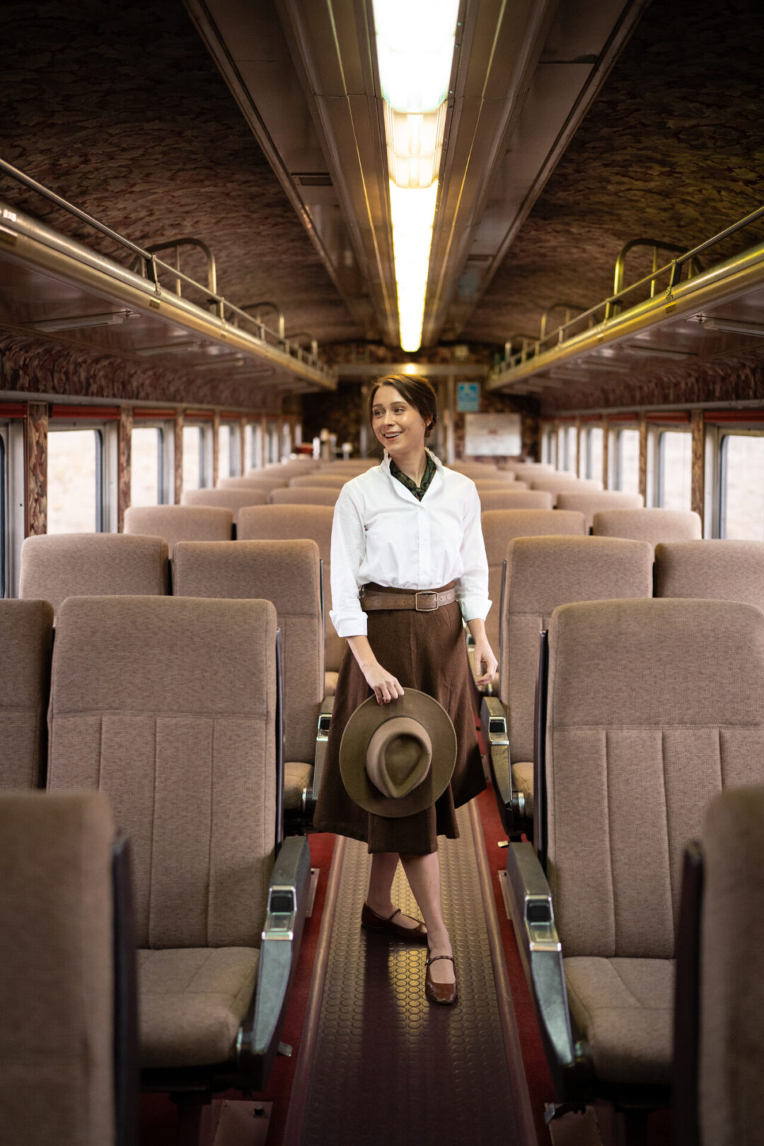 Travel Blogger Jordan Gassner smiling and standing in the middle aisle of a First Class car inside the Grand Canyon Railway