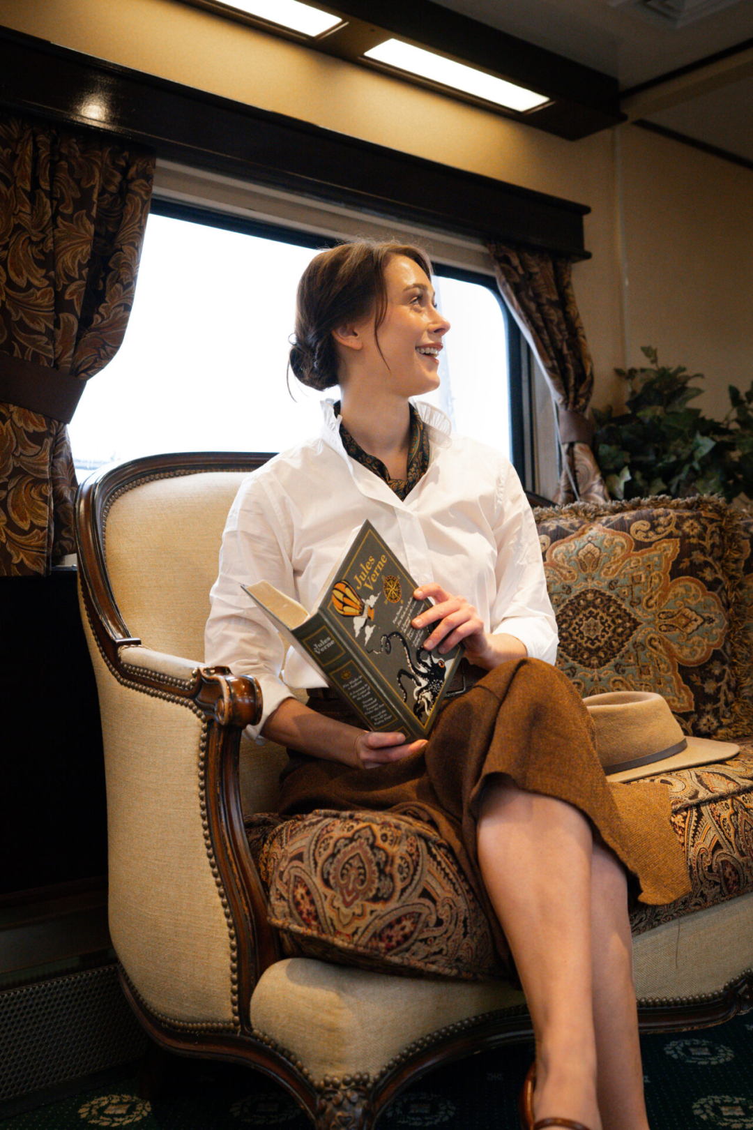 Travel Blogger Jordan Gassner reading a book and sitting on a loveseat inside a luxury parlor car along the Grand Canyon Railway in Williams, Arizona