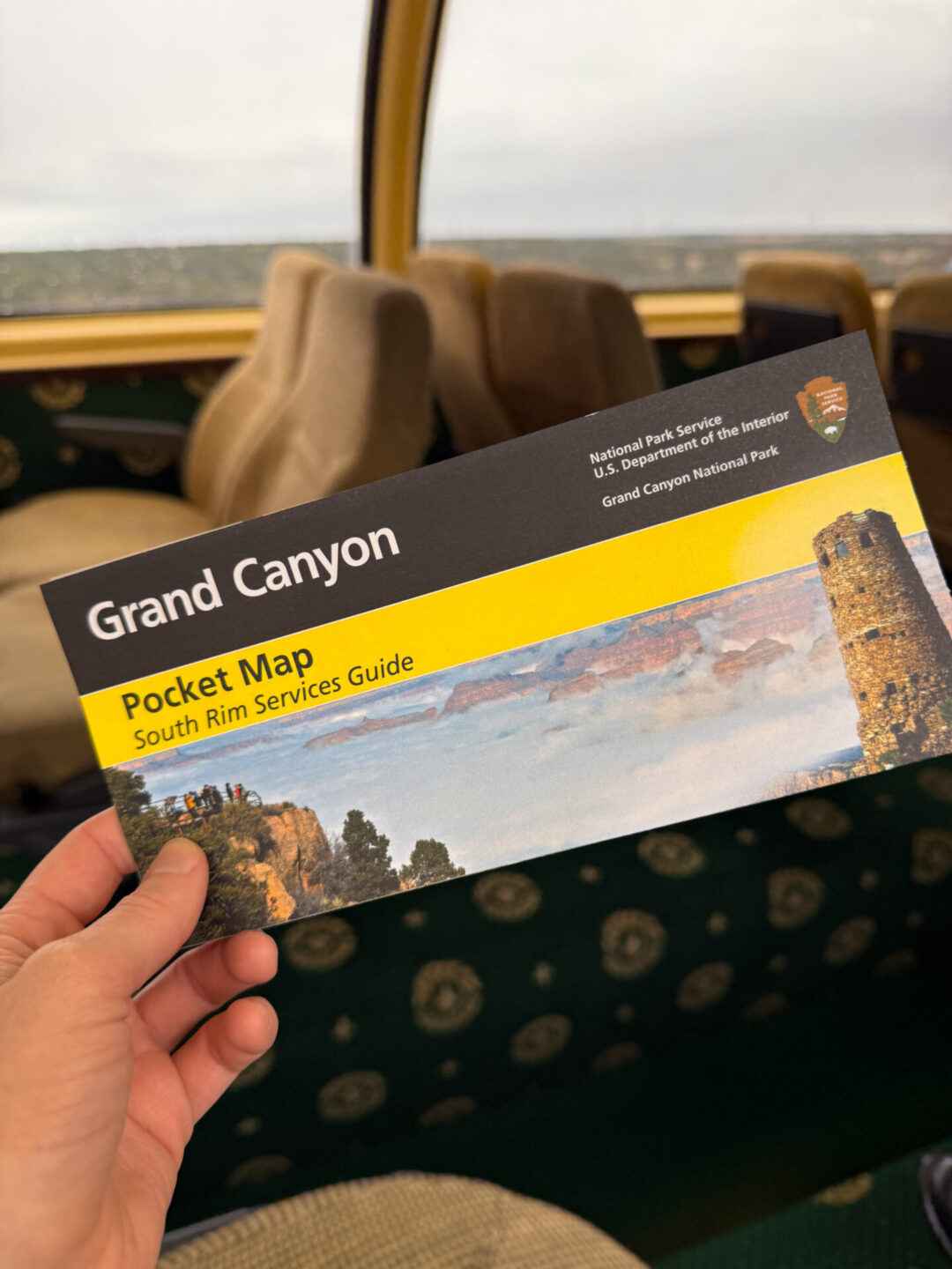 A woman's hand holding the Grand Canyon Pocket Map from the Observation Deck car on the Grand Canyon Railway