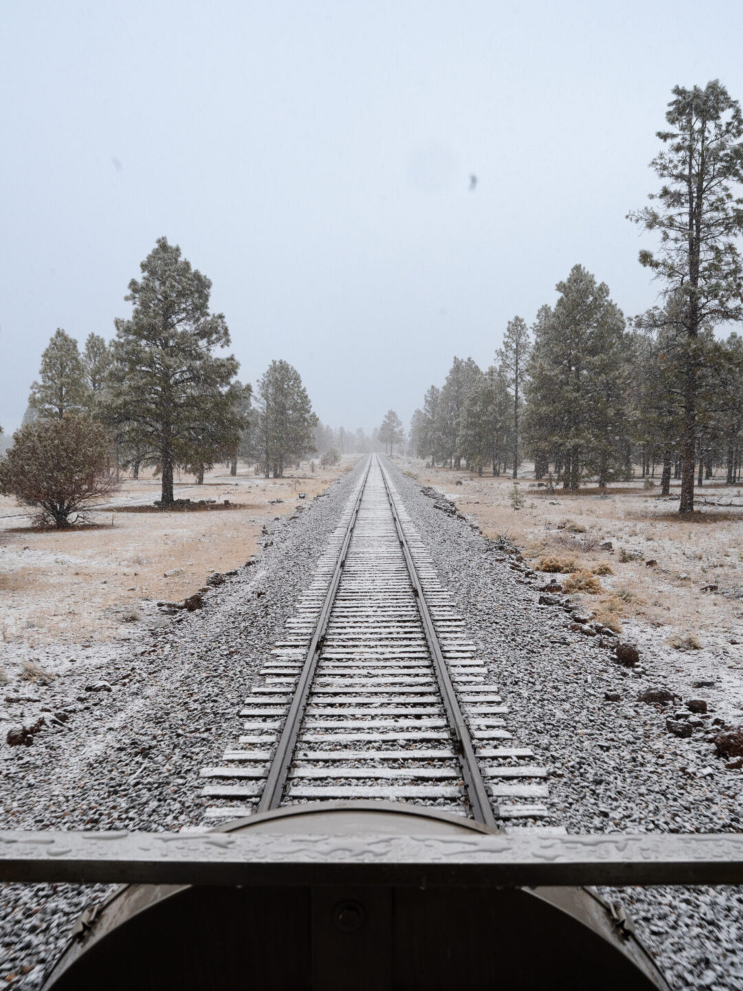 Grand Canyon in winter: Snow falling over the view of the train tracks from the back of the Observation Deck on the Grand Canyon Railway