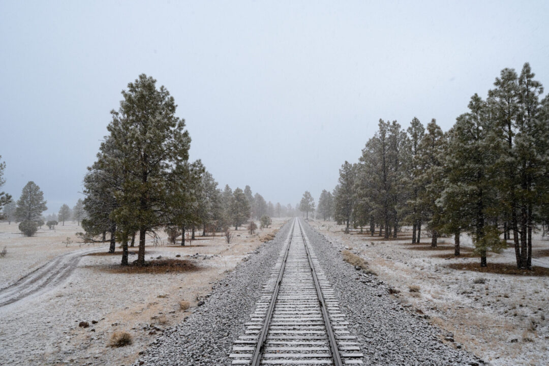 A landscape view of snow falling from the Observation Deck at the back of the Grand Canyon Railway