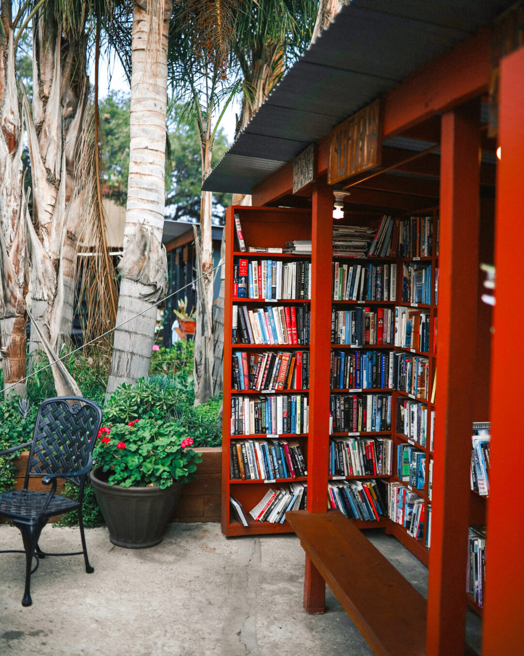 A bright red outdoor bookshelf housing hundreds of books at Barts Books in Ojai, California