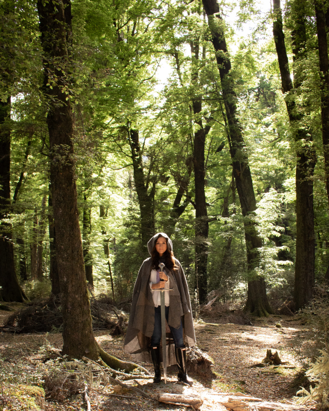 Travel Blogger Jordan Gassner wearing a cloak and holding Anduril "Lothlorien" in Paradise, New Zealand