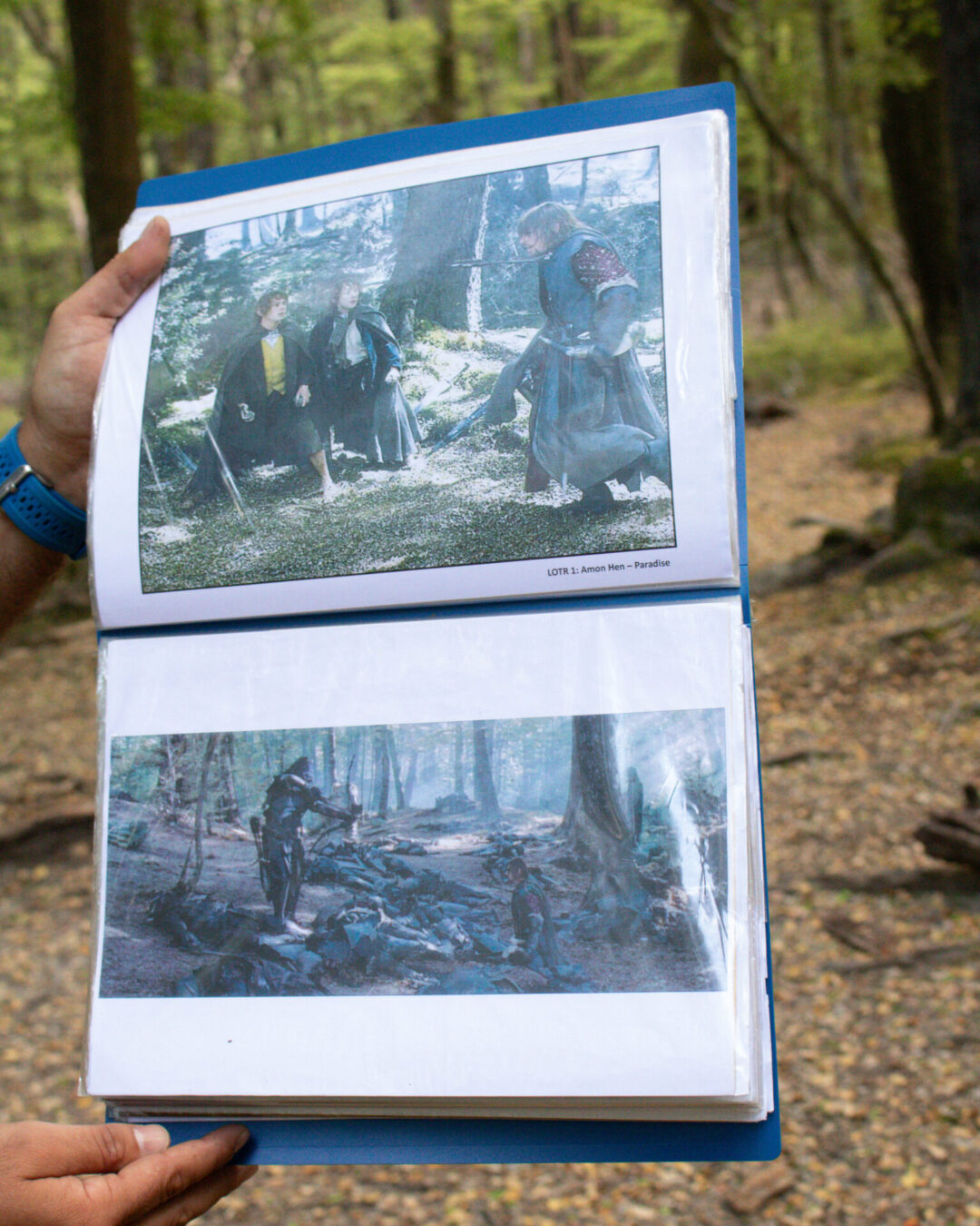 A guide holding up a binder with two pictures of the Lord of the Rings actors at "Amon Hen" in the real life location that it was filmed in New Zealand