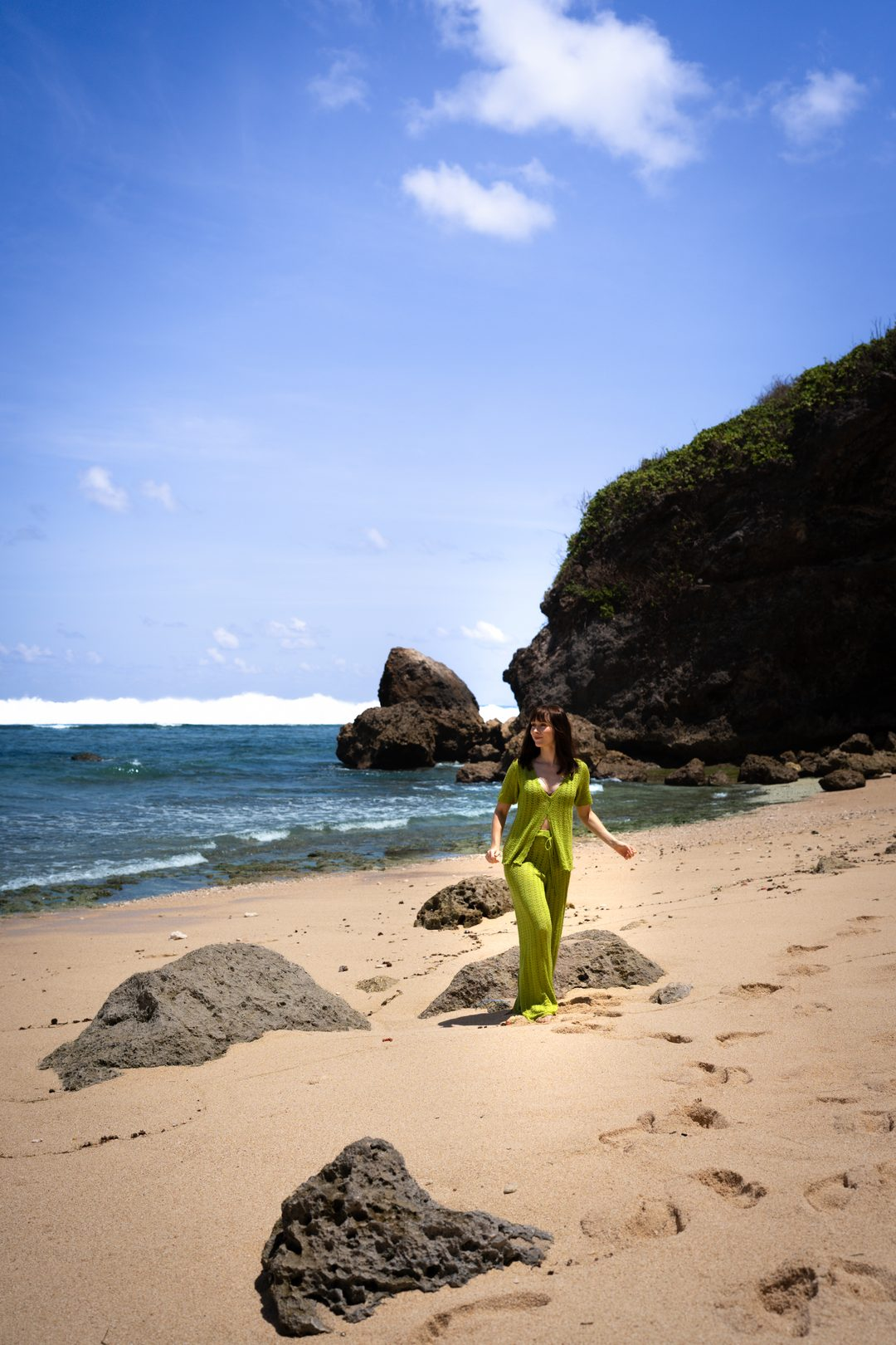 One Day in Uluwatu: Travel Blogger Jordan Gassner walking along Nyang Nyang Beach while wearing a green cover-up in Uluwatu, Indonesia